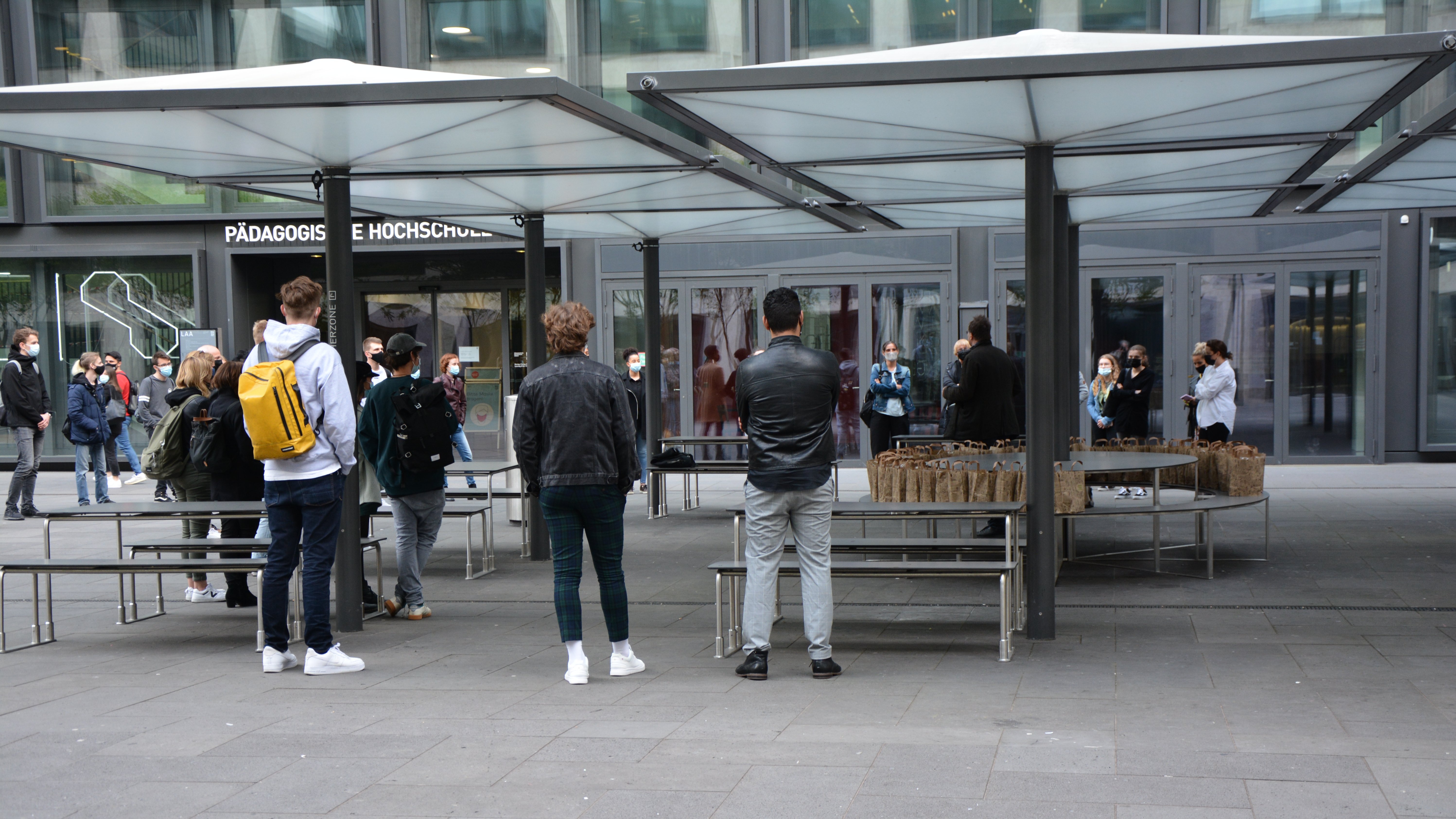 Die Gäste der Vernissage versammeln sich zur Begrüssung im Freien vor den Ausstellungs-räumlichkeiten an der PH Zürich. Jeder Gast erhält im praktischen Papiersack unter Einhaltung des Schutzkonzepts einen «Apéro-to-go».
